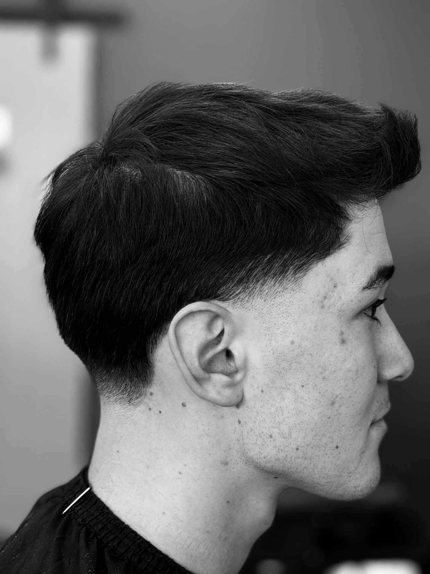 Clean fade and styled top, monochrome portrait